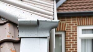 Dichtbij een verweerd zinken dakgoot met zilvergrijze patina op een Nederlands huis.