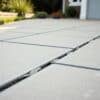 Oprit van grote betonplaten met zichtbare naden in een Nederlandse tuin.