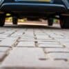 Stevige betonstenen en klinkers op een nette Nederlandse oprit met een geparkeerde auto.