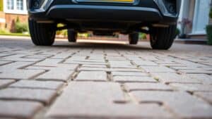 Stevige betonstenen en klinkers op een nette Nederlandse oprit met een geparkeerde auto.