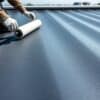 Installatie van een zwart EPDM rubber membraan op een plat dak door een vakman.