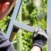 Glazier plaatst nieuw dubbelglas in een wit kunststof kozijn in een Nederlandse tuin.