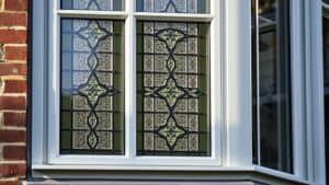 Glas in lood raam in dubbelglas op een Nederlandse bakstenen gevel, met zichtbaar loodwerk en moderne isolatie.