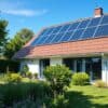 Tien zonnepanelen op het schuine dak van een Nederlands huis met een groene tuin op de voorgrond.